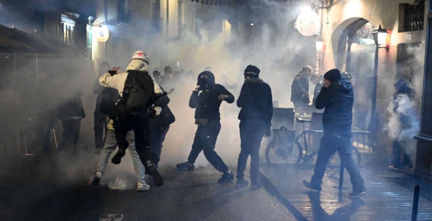 Protesters react in a cloud of tear gas during a demonstration in support to victims of police brutality, after events in Sainte-Soline and in pension protests, in Nantes, western France, on March 30, 2023. French police have been strongly criticized by rights groups for heavy-handed reaction to anti-government protests over the past month. (Photo by Sebastien SALOM-GOMIS / AFP)